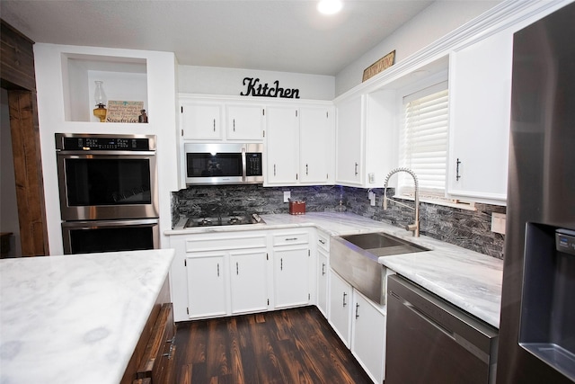 kitchen featuring dark wood-style floors, appliances with stainless steel finishes, a sink, and tasteful backsplash