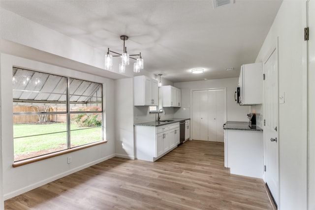 kitchen featuring light wood finished floors, baseboards, appliances with stainless steel finishes, white cabinetry, and a sink