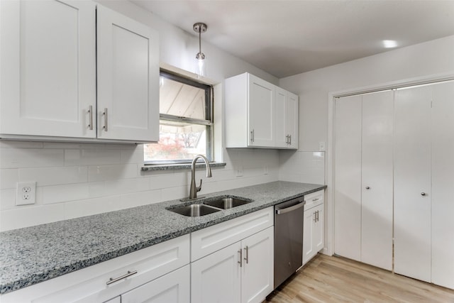 kitchen featuring light wood finished floors, white cabinets, a sink, light stone countertops, and dishwasher