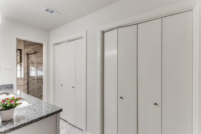 interior space featuring light stone countertops, visible vents, white cabinets, and a sink