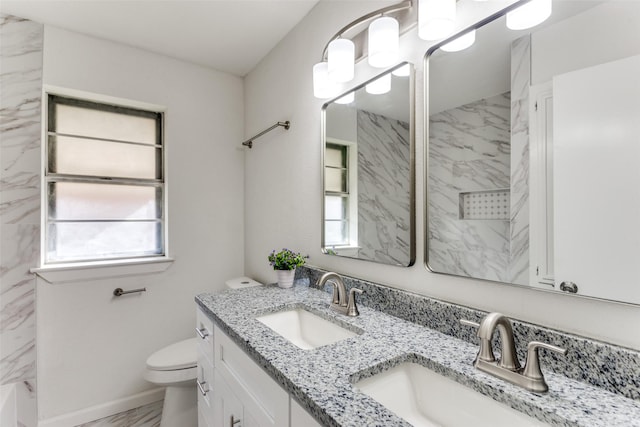 full bathroom featuring marble finish floor, double vanity, a sink, and toilet