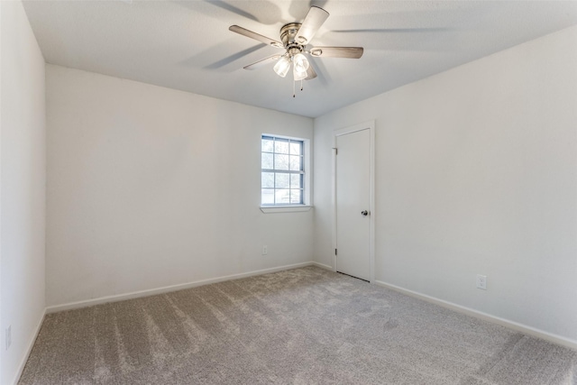 carpeted spare room featuring ceiling fan and baseboards