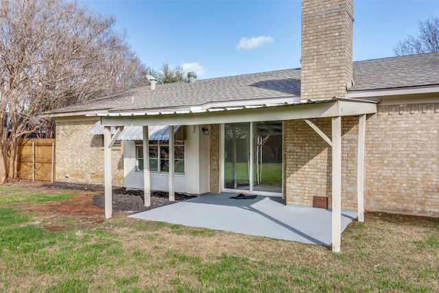 back of property with brick siding, a patio, a chimney, a shingled roof, and fence