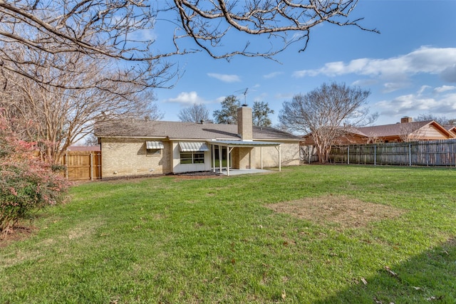 rear view of house featuring brick siding, a chimney, a lawn, a patio area, and a fenced backyard