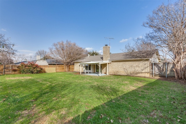 back of property featuring a patio, a chimney, a fenced backyard, and a lawn