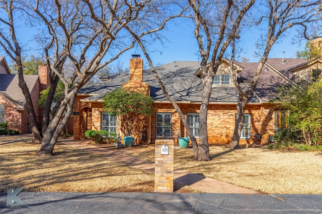 view of front of home featuring brick siding and a chimney