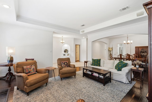 living room with arched walkways, a raised ceiling, a notable chandelier, and hardwood / wood-style flooring