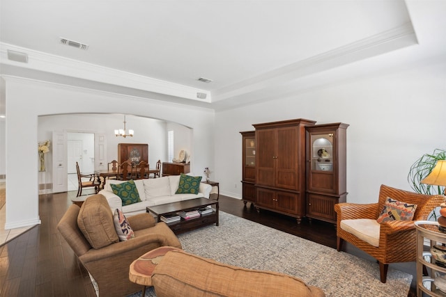 living room with dark wood-style flooring, a raised ceiling, visible vents, and a notable chandelier