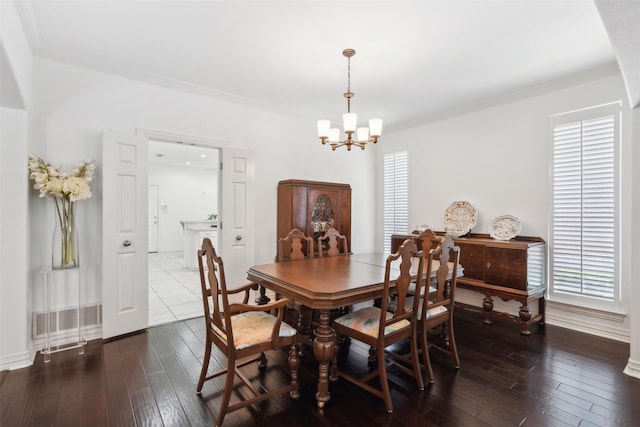 dining room with hardwood / wood-style flooring, plenty of natural light, crown molding, and an inviting chandelier