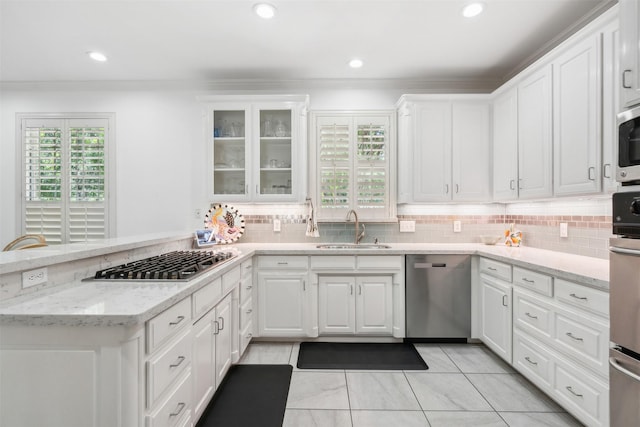 kitchen with a peninsula, white cabinetry, appliances with stainless steel finishes, and a sink