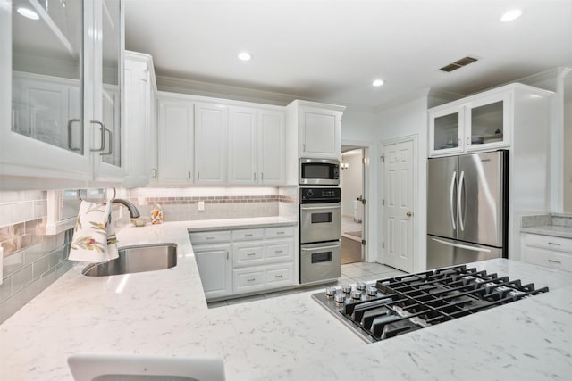 kitchen featuring light stone counters, a sink, visible vents, appliances with stainless steel finishes, and tasteful backsplash