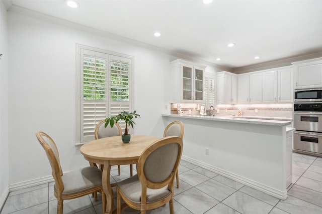 kitchen with white cabinetry, ornamental molding, appliances with stainless steel finishes, decorative backsplash, and glass insert cabinets