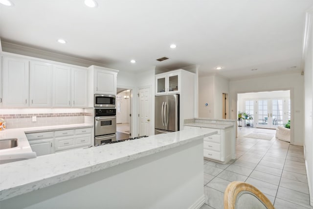 kitchen with french doors, crown molding, stainless steel appliances, visible vents, and a peninsula