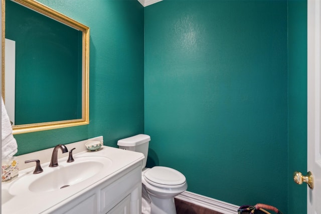 bathroom featuring a textured wall, vanity, and toilet