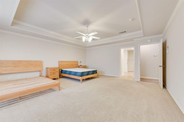 bedroom with carpet floors, visible vents, a tray ceiling, and ornamental molding