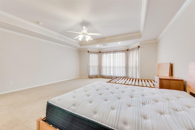 bedroom with baseboards, ceiling fan, ornamental molding, a tray ceiling, and carpet floors