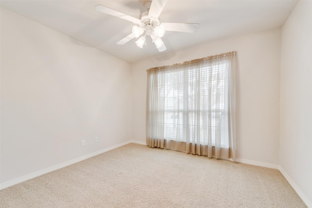 carpeted spare room featuring ceiling fan and baseboards