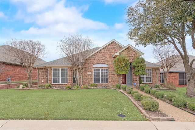 view of front of home featuring brick siding, a front lawn, and roof with shingles