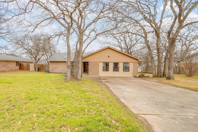 view of front of home with driveway, a front yard, fence, and brick siding