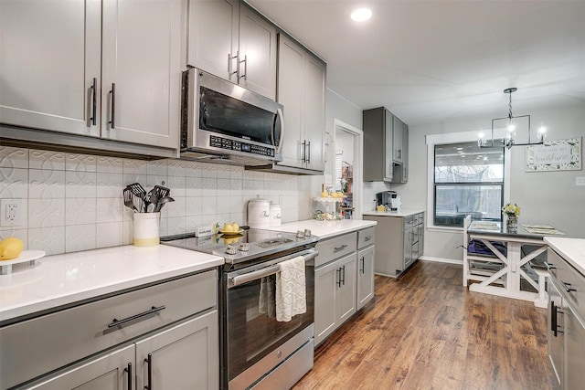 kitchen featuring stainless steel appliances, wood finished floors, gray cabinets, and decorative backsplash