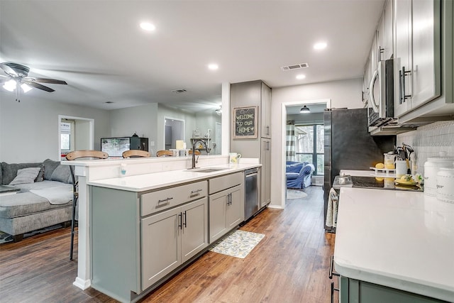 kitchen featuring a sink, visible vents, a kitchen breakfast bar, open floor plan, and appliances with stainless steel finishes