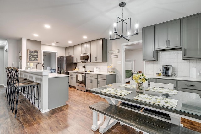 kitchen featuring appliances with stainless steel finishes, a kitchen breakfast bar, gray cabinetry, and wood finished floors