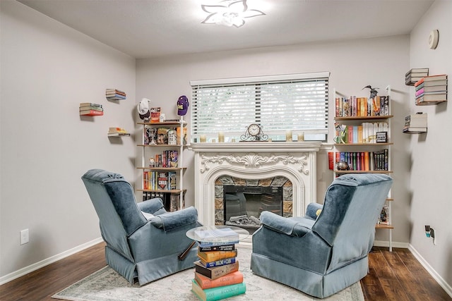 living area featuring baseboards, wood finished floors, and a tile fireplace