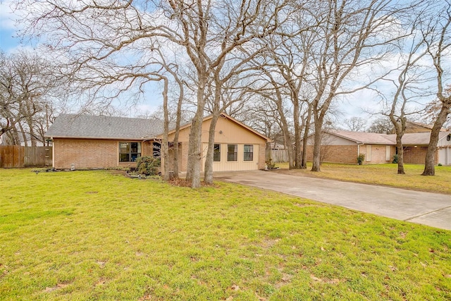 view of side of home with a yard, concrete driveway, brick siding, and fence