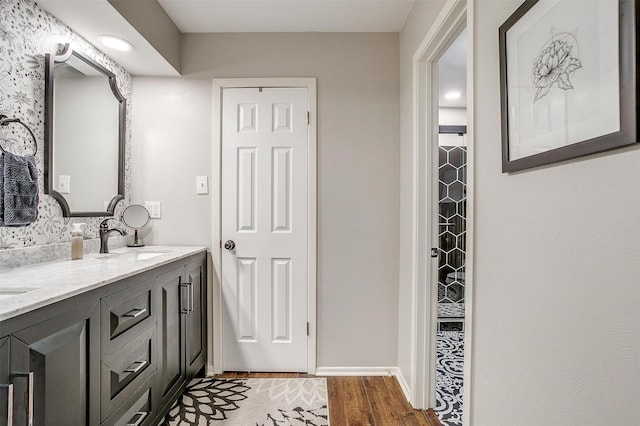 bathroom featuring double vanity, a sink, baseboards, and wood finished floors