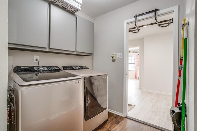 laundry room featuring cabinet space, baseboards, washer and clothes dryer, and wood finished floors