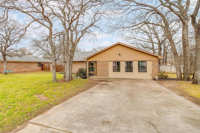 view of front of house with a front yard, fence, concrete driveway, and brick siding