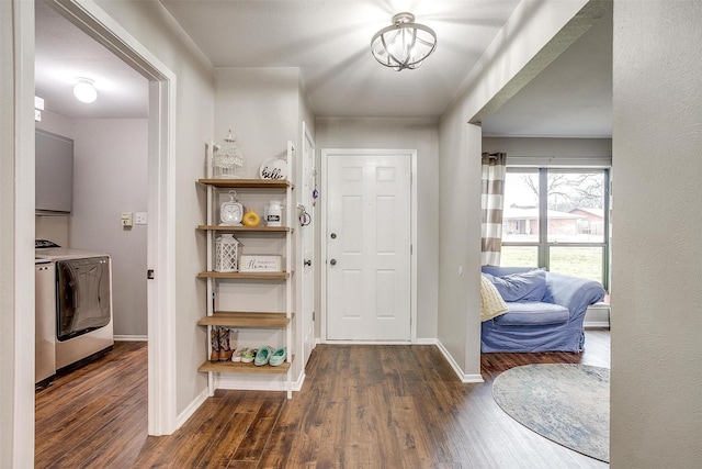 foyer featuring dark wood-type flooring, washer and clothes dryer, and baseboards