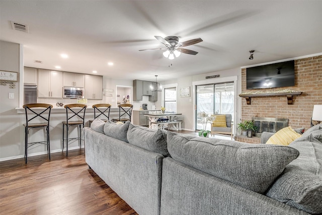 living area with dark wood finished floors, recessed lighting, visible vents, a ceiling fan, and a brick fireplace