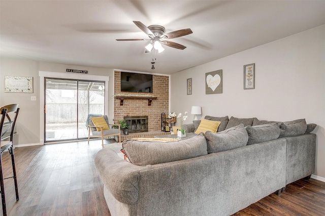 living room with dark wood-type flooring, a fireplace, a ceiling fan, and baseboards