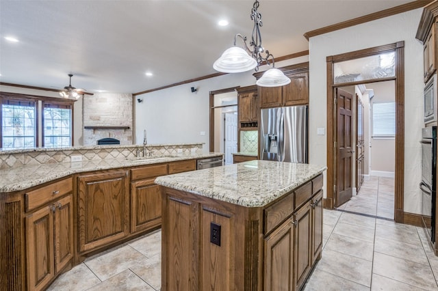 kitchen with a kitchen island, a sink, ornamental molding, appliances with stainless steel finishes, and tasteful backsplash