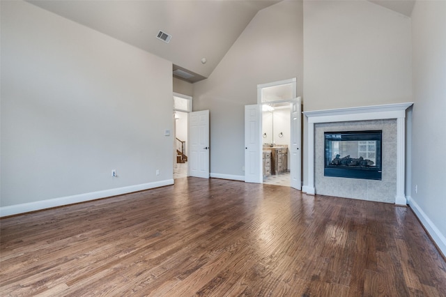 unfurnished living room featuring visible vents, baseboards, a tiled fireplace, and wood finished floors