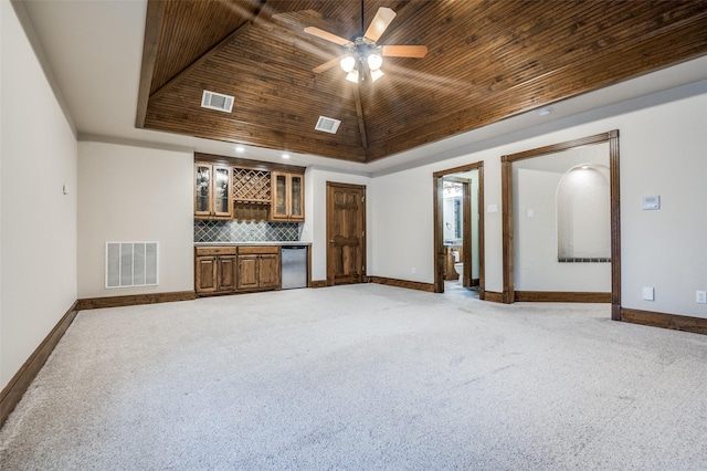 unfurnished living room featuring a raised ceiling, visible vents, wooden ceiling, and indoor bar