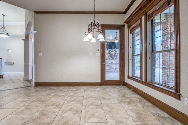 unfurnished dining area with light tile patterned floors, a chandelier, baseboards, decorative columns, and crown molding