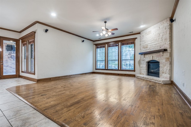 unfurnished living room featuring ornamental molding, a fireplace, baseboards, and wood finished floors