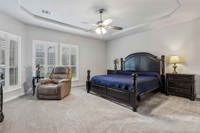 bedroom with a tray ceiling, carpet flooring, visible vents, and baseboards