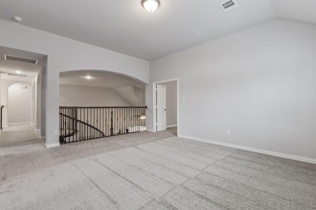 unfurnished room with lofted ceiling, visible vents, arched walkways, and carpet flooring