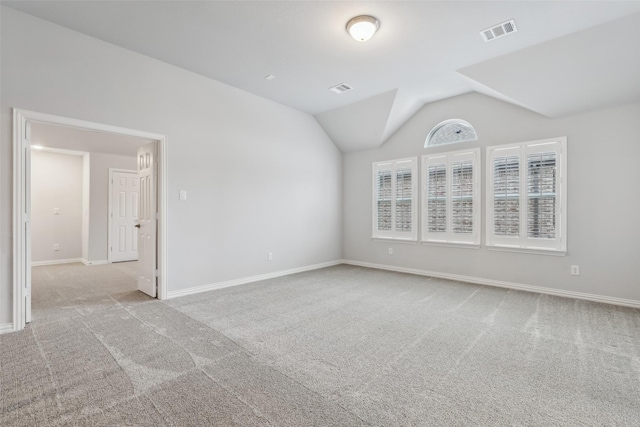 empty room with vaulted ceiling, carpet, visible vents, and baseboards