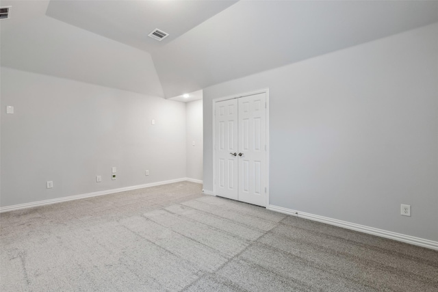 unfurnished room with carpet, visible vents, and vaulted ceiling