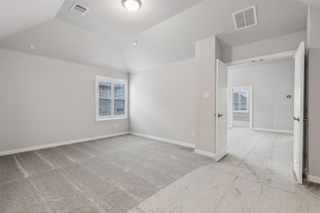 unfurnished room with lofted ceiling, a wealth of natural light, light carpet, and visible vents