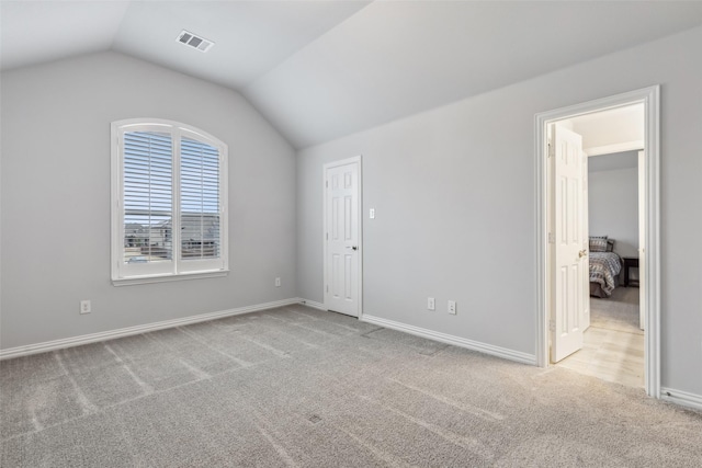 unfurnished bedroom featuring lofted ceiling, baseboards, visible vents, and carpet flooring