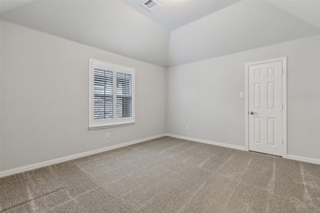 carpeted spare room with baseboards, visible vents, and vaulted ceiling