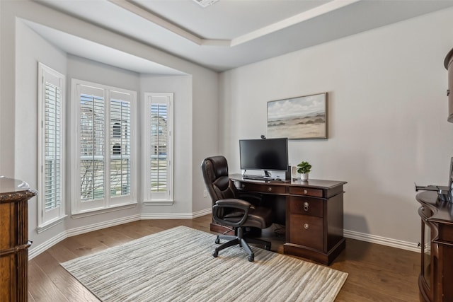 office area with a raised ceiling, wood finished floors, and baseboards