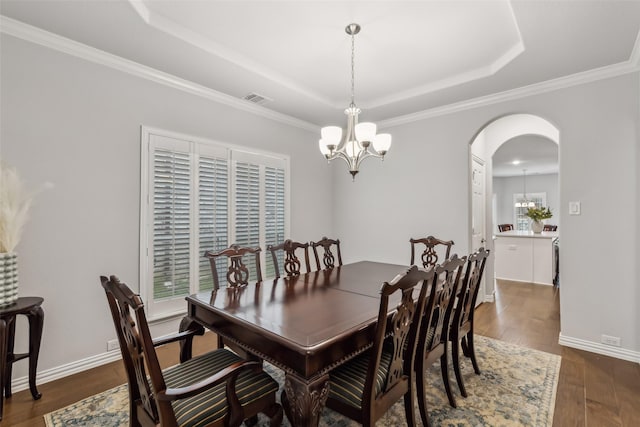 dining space featuring dark wood-style floors, arched walkways, a notable chandelier, a raised ceiling, and visible vents