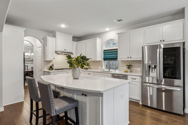 kitchen with dark wood finished floors, arched walkways, stainless steel appliances, and a sink