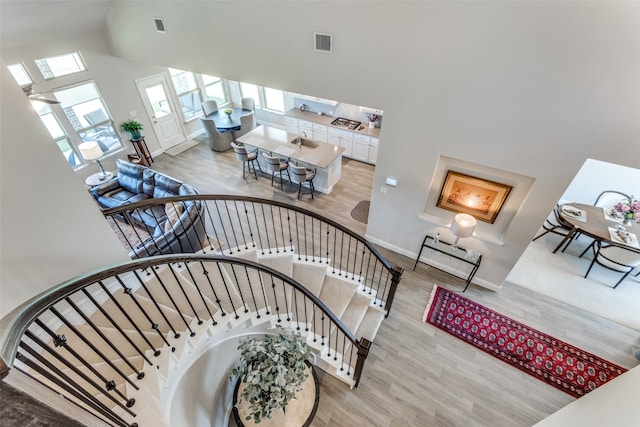 staircase featuring visible vents, a towering ceiling, and wood finished floors